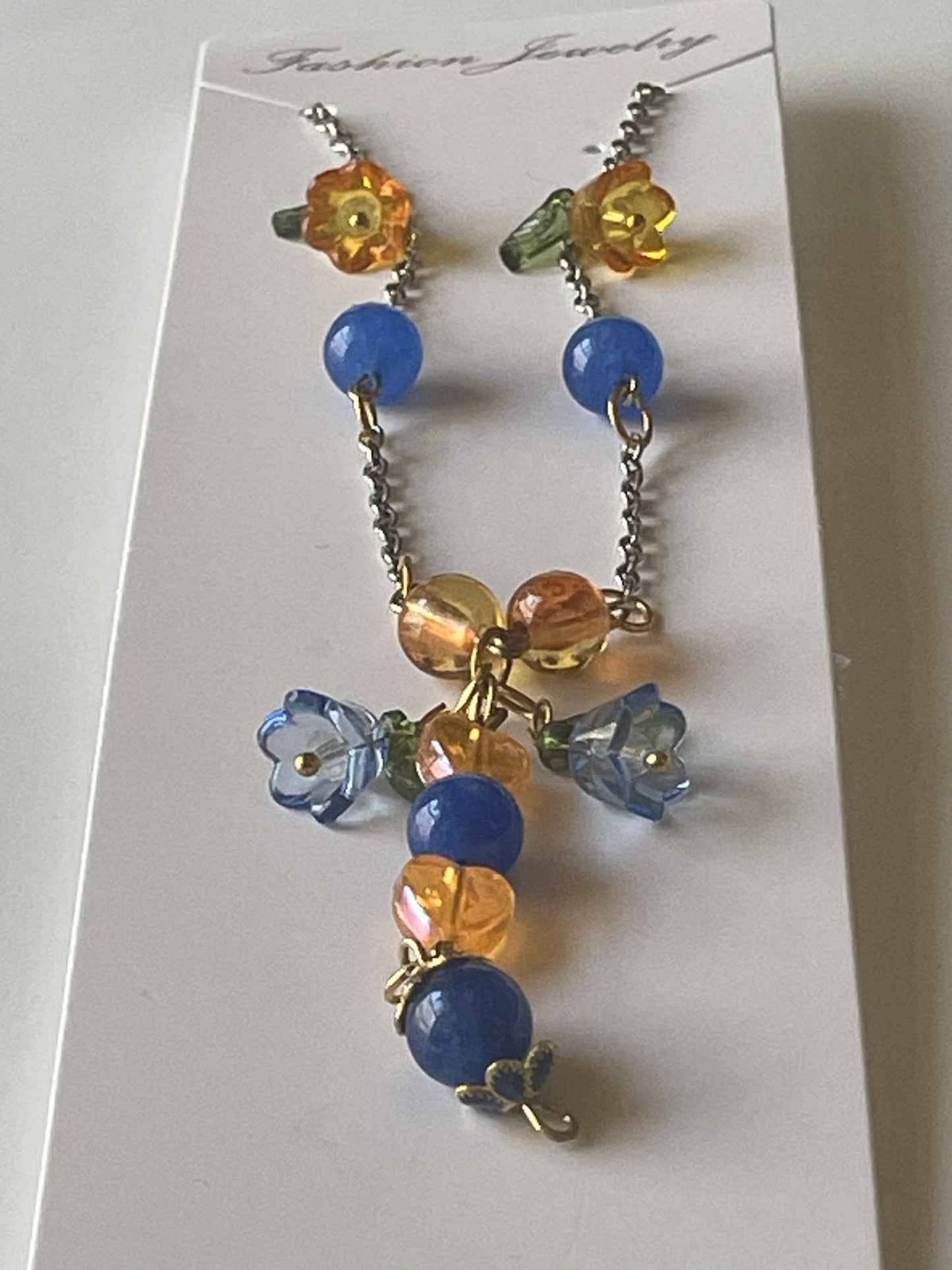 Gold and silver chain necklace with orange acrylic beads, blue kyanite beads, and decorative bead caps by Sylvia Leroux.