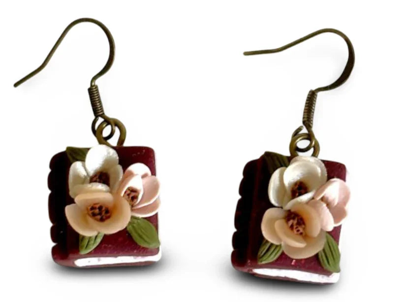 Maroon book-shaped polymer clay dangle earrings with floral designs and brass hooks, handcrafted jewelry by Melissa Cortinas.