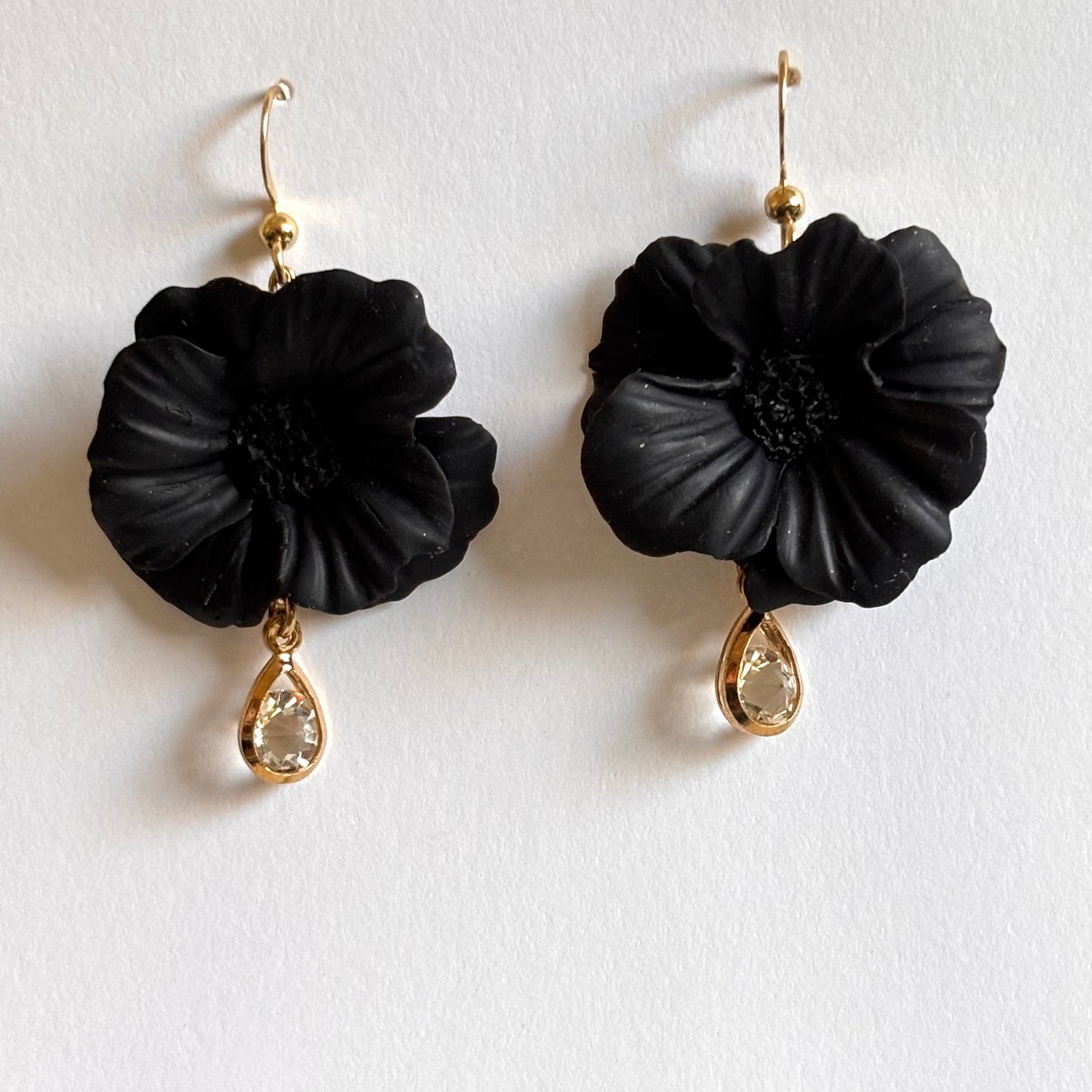Melissa Cortinas black polymer clay dangle earrings with cubic zirconia pendant featuring floral bloom design.