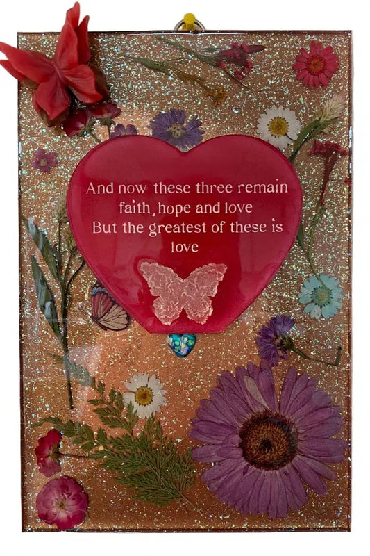 Decorative resin plaque featuring 1 Corinthians 13:13 with dried flowers, butterflies, and heart design, 12x8 inches by Brigitte Rosson.