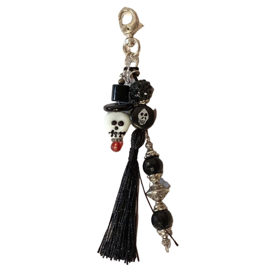 Black skull charms keychain with tassel and lobster clasp, featuring Ysleta Mission Gift Shop branding and decorative metal details.