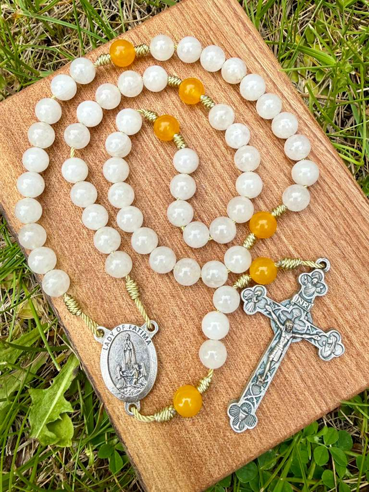 White and yellow Catholic rosary with Our Lady of Fatima image, five-decade Christian rosary by Liza Murphy, featuring beads and crucifix.