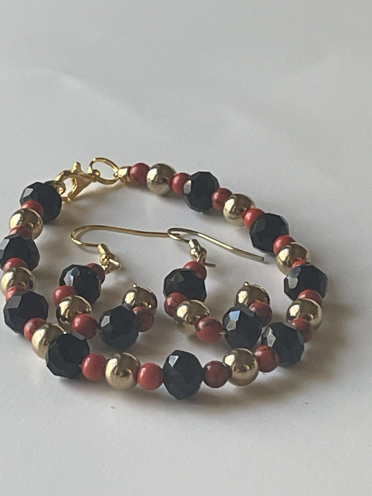 Sylvia Leroux jewelry set with 7-inch bracelet and matching earrings, red stone beads, gold metal beads, and black faceted glass beads.