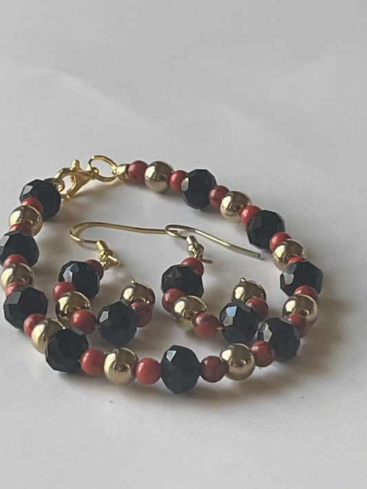Sylvia Leroux jewelry set with 7-inch bracelet and matching earrings featuring red stone beads, gold metal accents, and black faceted glass beads.