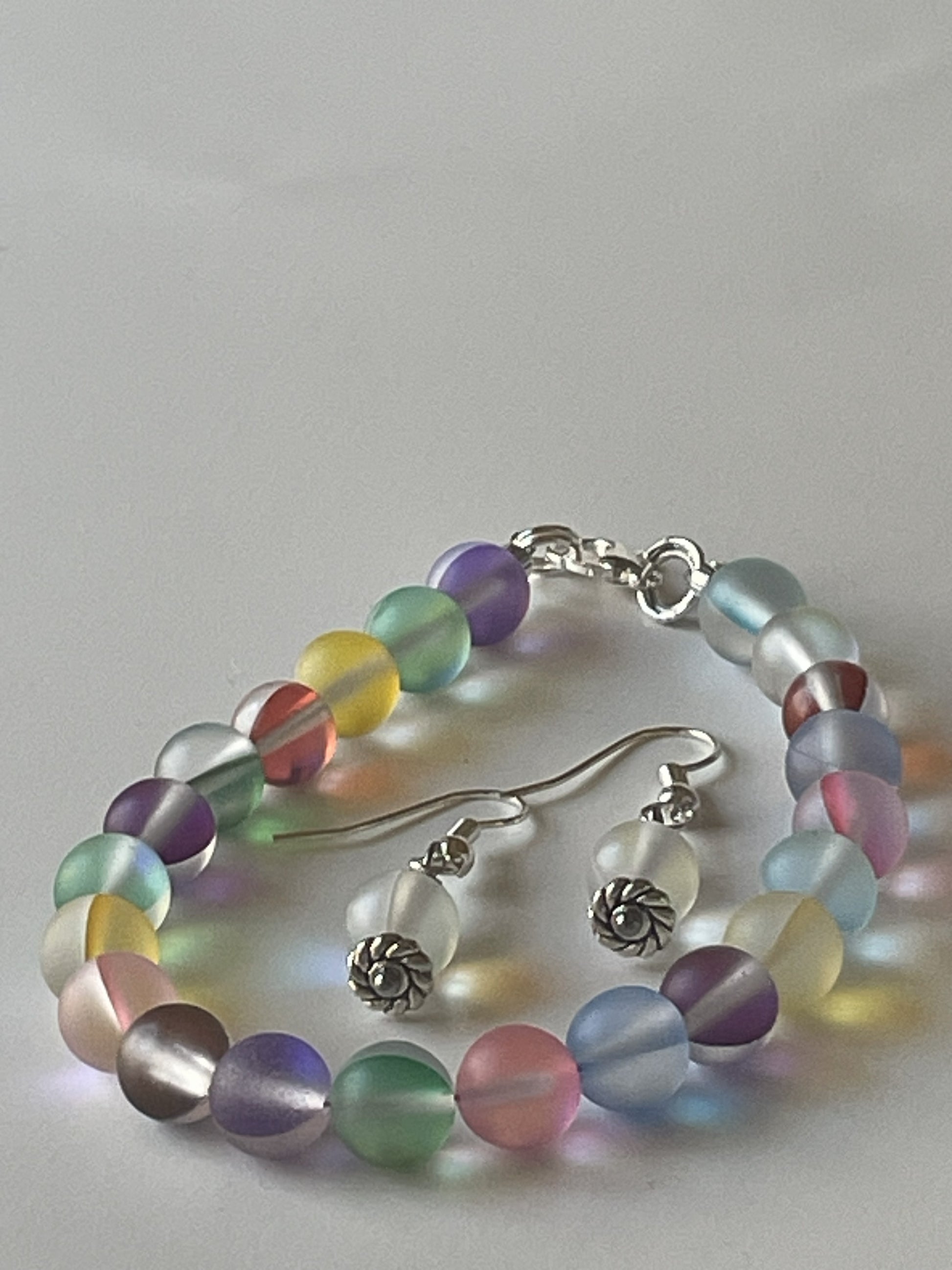 Mixed color iridescent bracelet and matching earrings set by Sylvia Leroux featuring 8mm beads, silver lobster clasps and hooks.
