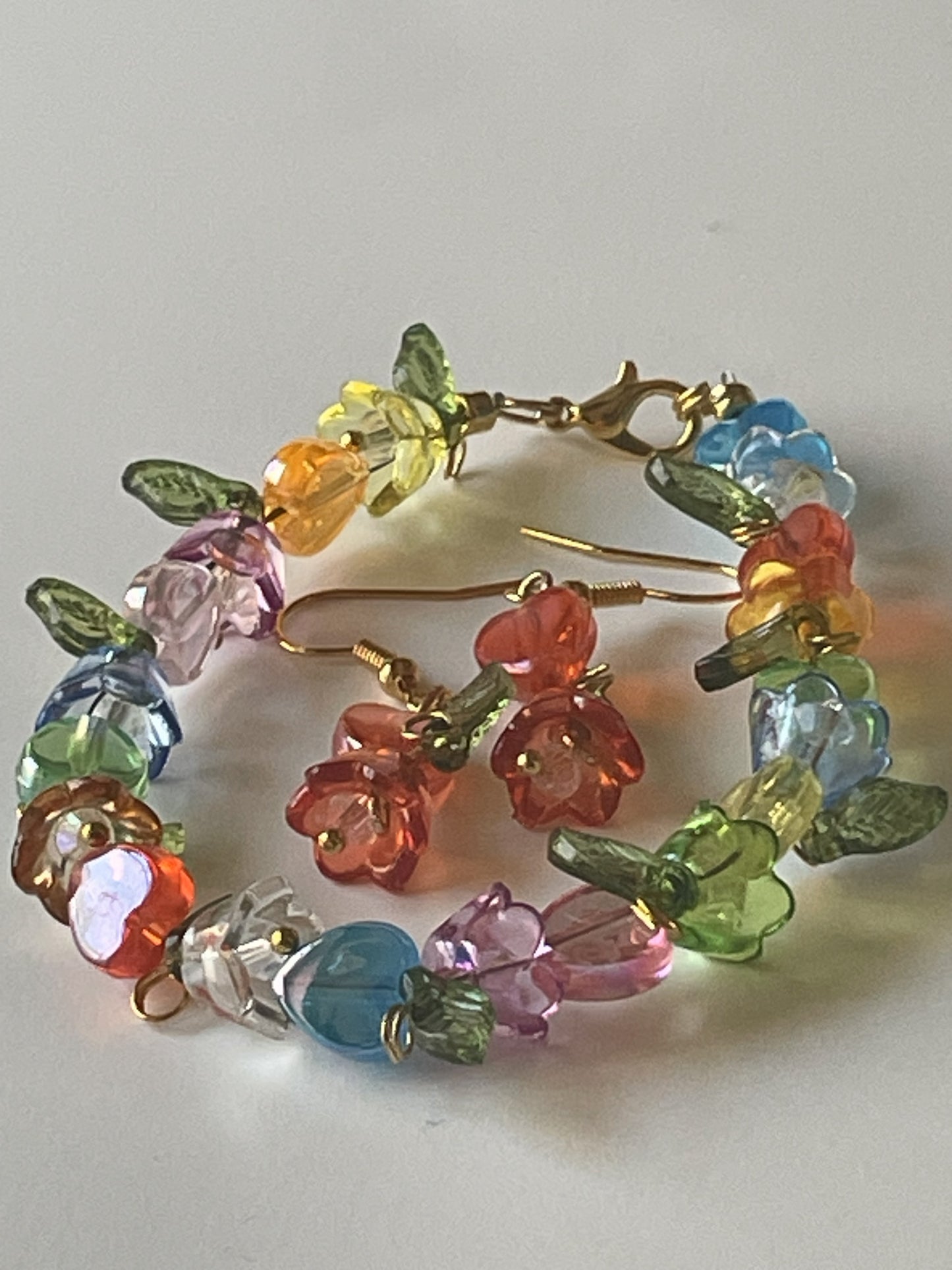 Acrylic flower bead bracelet and matching dangle earrings set with mixed colors, gold lobster clasp, and hooks by Sylvia Leroux.