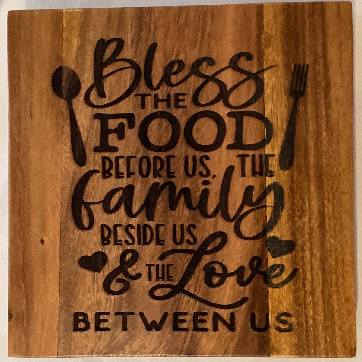 Wood etched 10-inch pot holder featuring food and family motifs, crafted by Ysleta Mission Gift Shop.