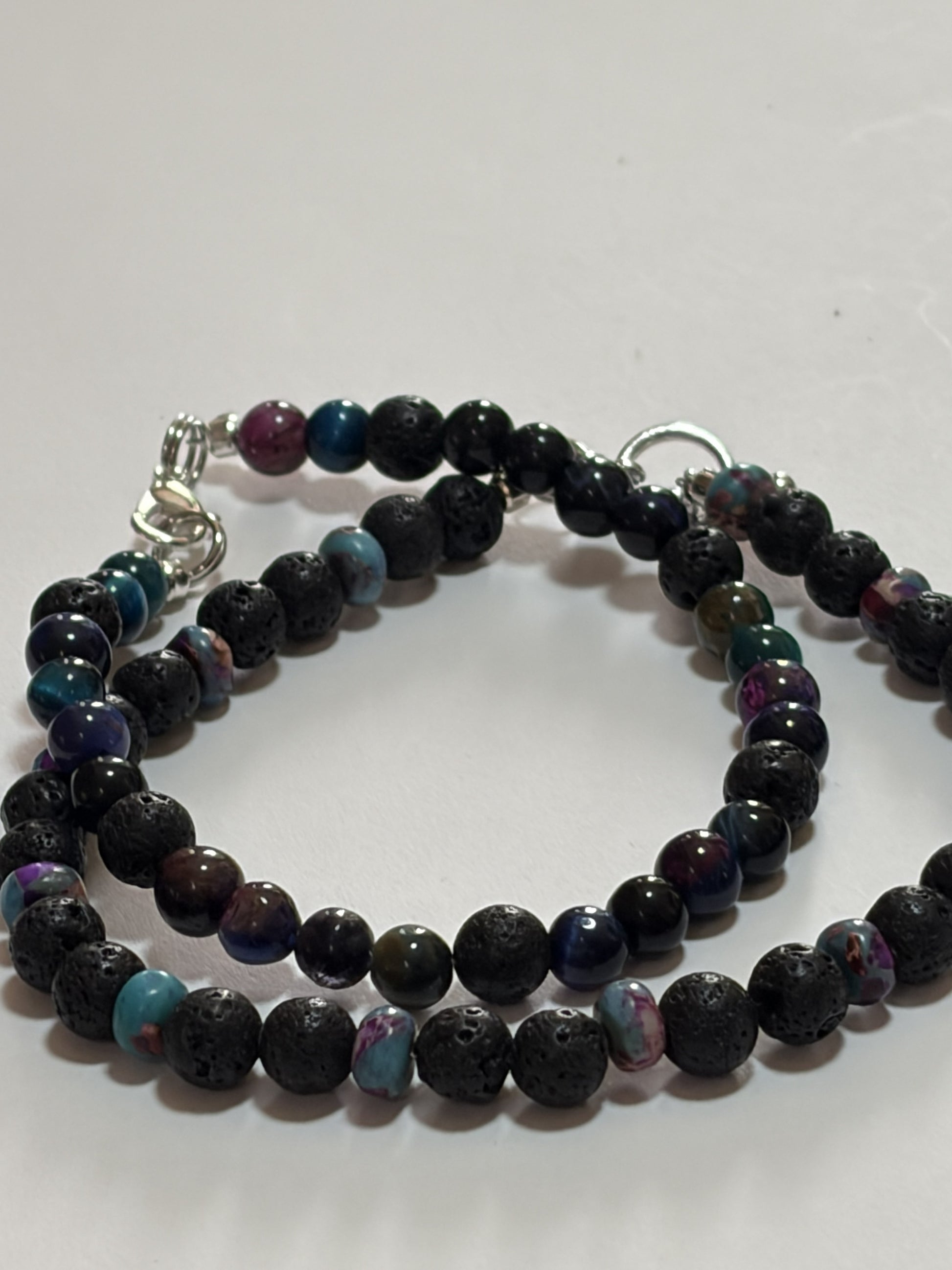 Black lava stone bracelet set by Sylvia Leroux with 6mm beads, silver lobster clasp, and blue cats eye accents for couples.
