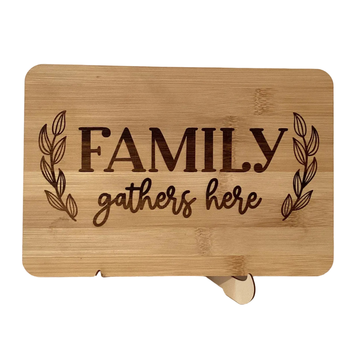 Wood burned plaque with "Family Gathers Here" design on 7-inch wood, displayed on an easel, from Ysleta Mission Gift Shop.
