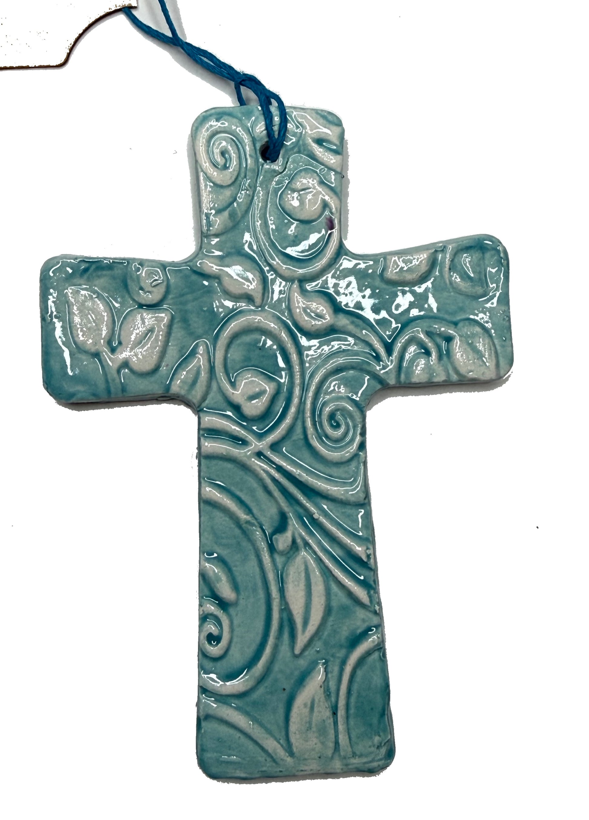 Teal ceramic cross with leaf pattern by Lorena Williams, decorative wall art with intricate leaf design.