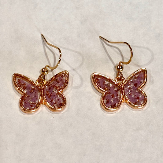 Gold tone butterfly dangle earrings with light purple confetti glitter in clear resin by Melissa Cortinas jewelry.