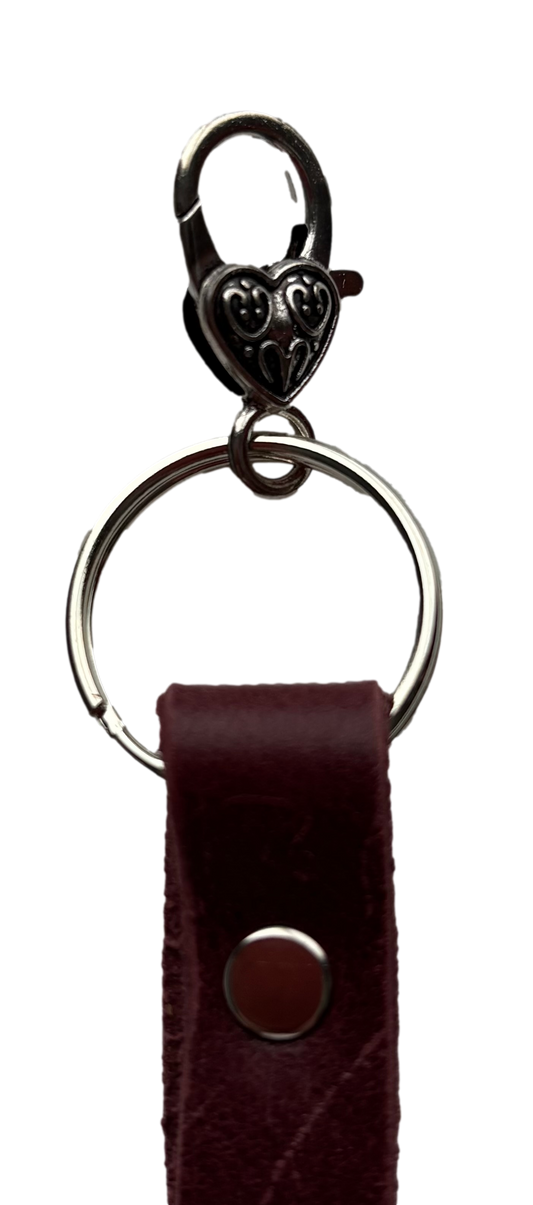 Silver butterfly keychain by Consuelo Barraza attached to a handbag, showcasing its delicate metal design and secure snap closure.