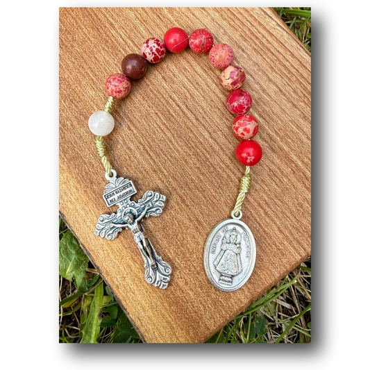 Infant of Prague Catholic rosary with red imperial jasper and white jade beads, featuring a small crucifix and medallion.