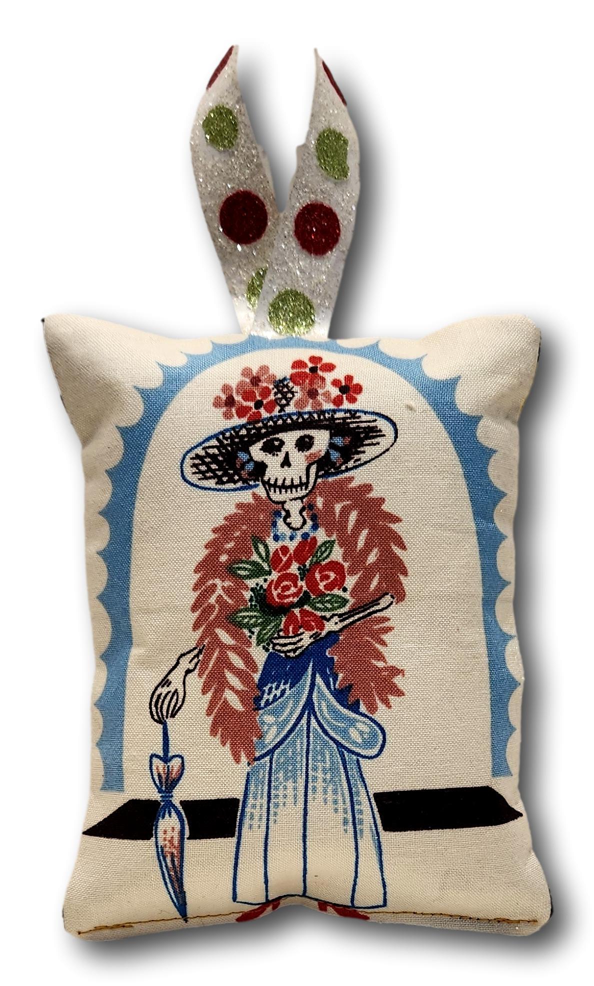 Decorative cotton pillow ornament with Day of the Dead theme, featuring various designs, 5x4 inches, from Ysleta Mission Gift Shop.