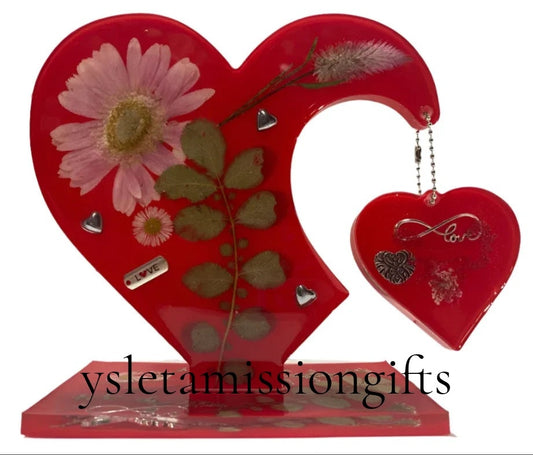 Resin heart artwork by Brigitte Rosson with dried flowers and silver love charms, perfect for home decor and artistic display.