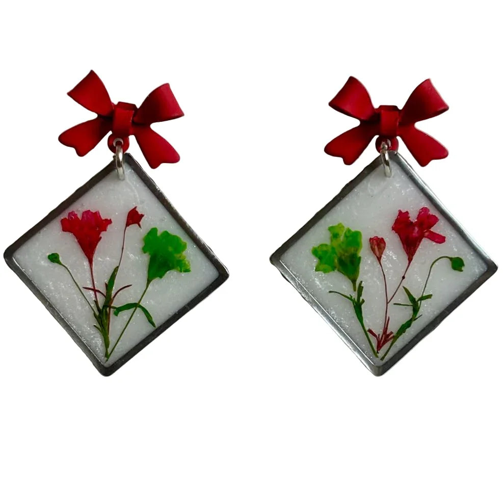 Resin pressed flower dangle earrings with red bow stud accents, handmade jewelry by Melissa Cortinas, 1x1 inches.